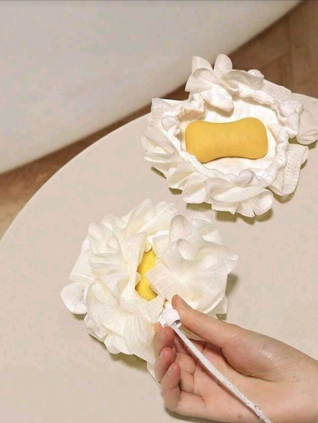 Flower-shaped bath loofah with built-in yellow soap, soft petals for gentle exfoliation, hand pulling cord to reveal soap