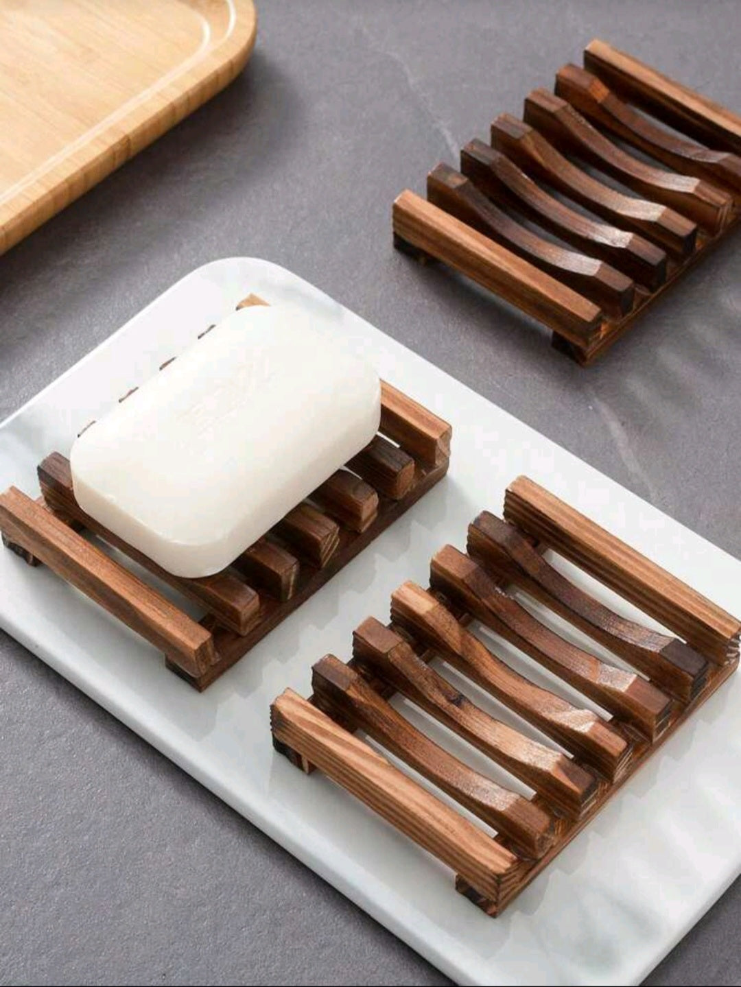 Dark wood bamboo soap tray holding a bar of soap on a bathroom counter, eco-friendly and stylish